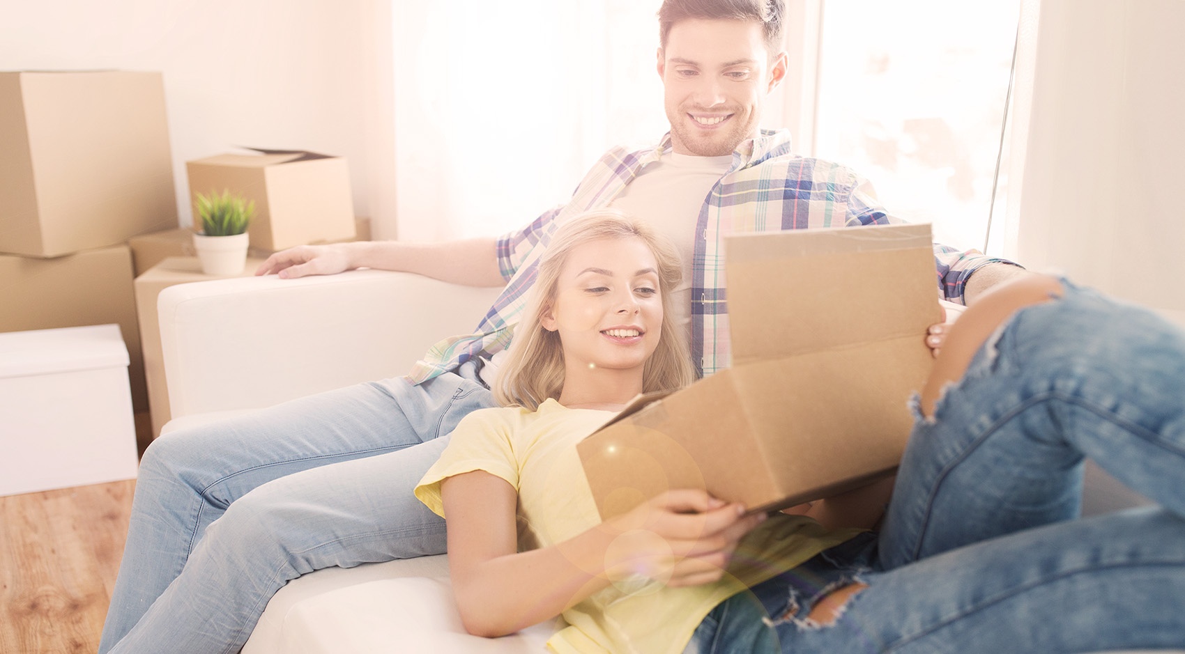 Couple sitting on sofa with a cardboard box 